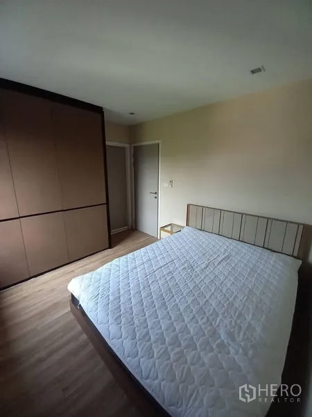 Townhouse for rent in Suan Luang, Bangkok - Bright bedroom with large fitted wardrobe, wood floors and neutral walls.