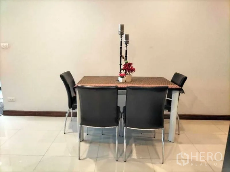 Condominium for rent in Watthana, Bangkok - Four-seat dining table with black chairs and decorative centerpiece.