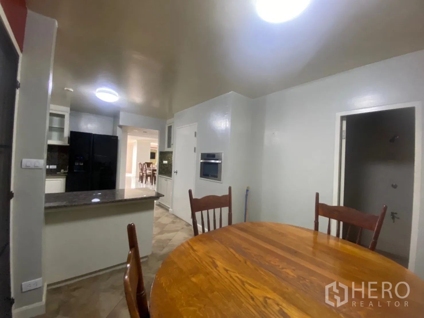 Condominium for rent or sale in Watthana, Bangkok - Breakfast nook beside the kitchen with a round wooden table and chairs.