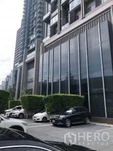 Condominium for rent or sale in Khlong Toei, Bangkok - Ground-level parking and landscaped frontage of The Crest building.