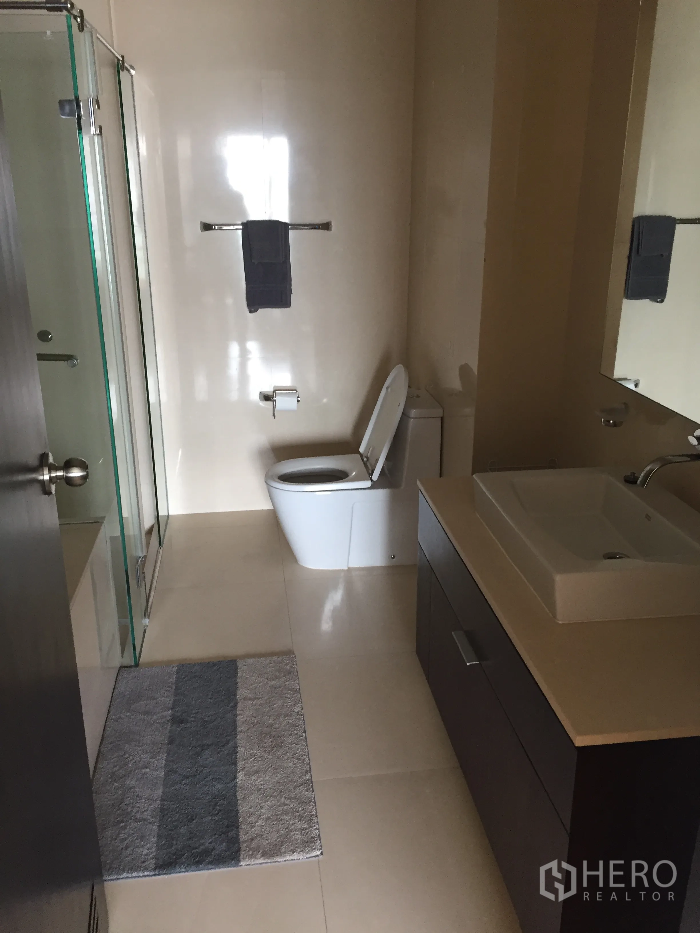 公寓 出租在Watthana, Bangkok - 宽敞浴室，玻璃淋浴间、大镜子与洗手台。