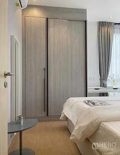 公寓 出租在Watthana, Bangkok - 卧室一角配嵌入式衣柜与床边小桌，纱帘引入充足自然光。