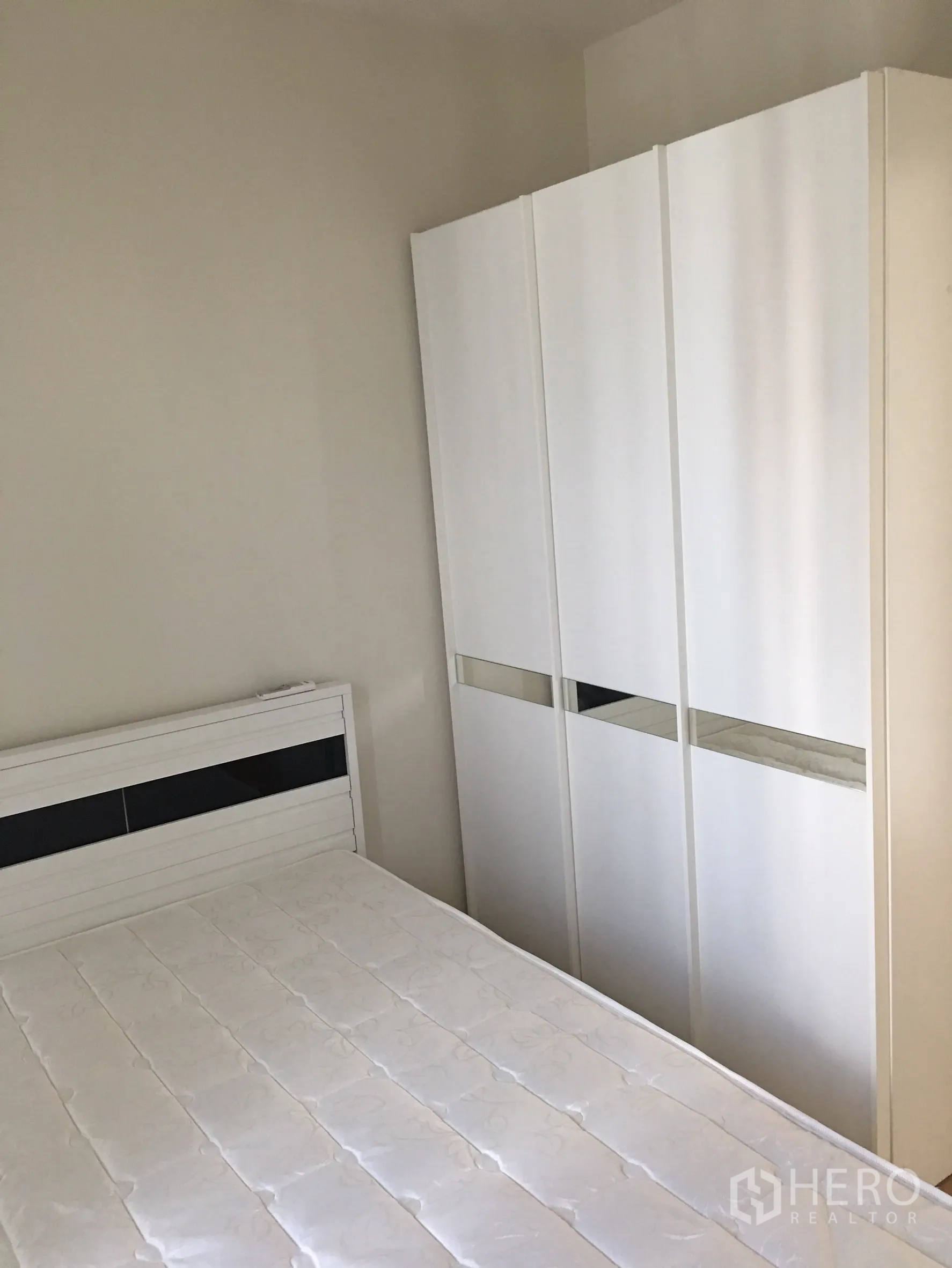 Condominium for rent in Phaya Thai, Bangkok - Second bedroom with white bed frame and sliding door wardrobe in neutral tones.