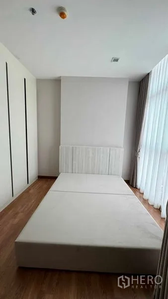 公寓 出租在Bang Na, Bangkok - 极简卧室，平台床架、内置衣柜与高窗薄帘。
