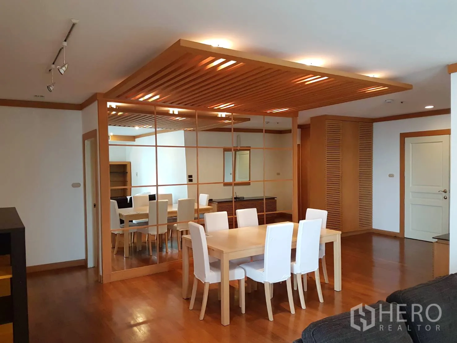 公寓 出租在Pathum Wan, Bangkok - 开放式客餐厅，木质装饰、轨道灯与镜面特色墙，空间感通透。