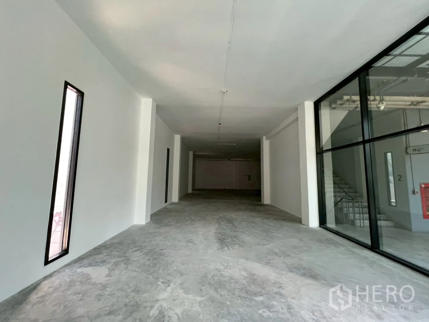 零售空间 for rent in Khlong Toei, Bangkok - 狭长型商铺，设窄条高窗与临楼梯的玻璃入口。
