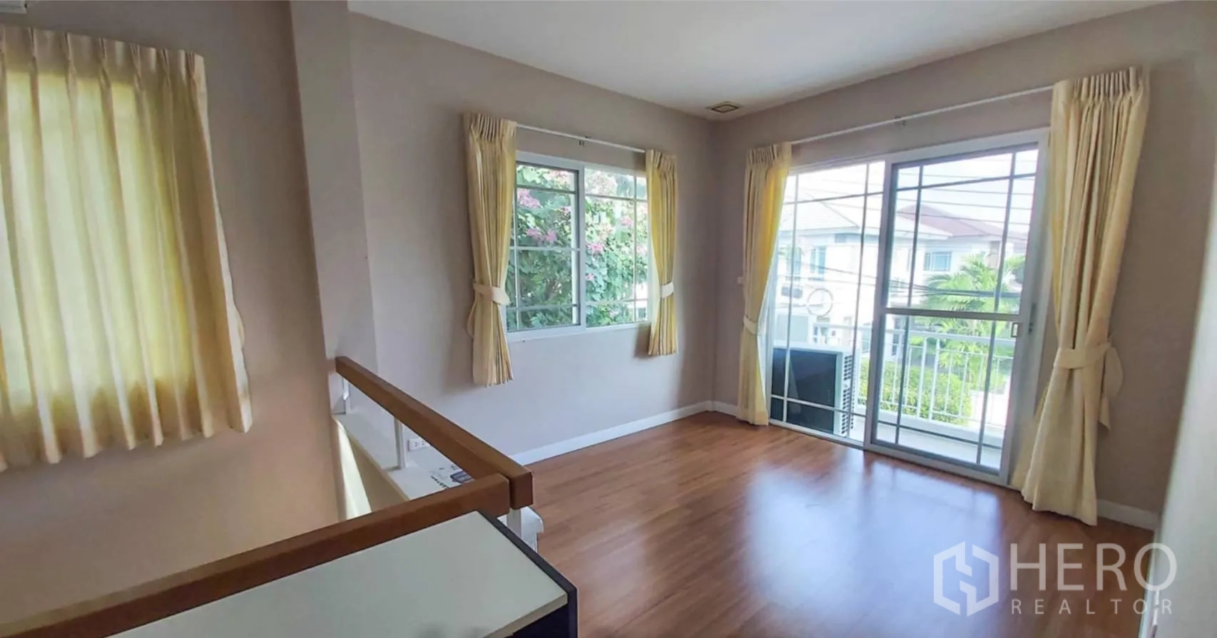 Detached House for sale in Bang Kapi, Bangkok - Upstairs landing with wood floors, corner windows and sliding door to a balcony.