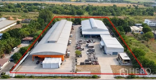 Factory for sale in Lat Lum Kaeo, Pathum Thani - Bird’s-eye view of two large warehouse buildings with open storage areas and loading aprons within a fenced industrial site.