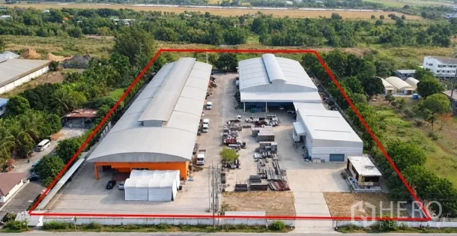 Factory for sale in Lat Lum Kaeo, Pathum Thani - Bird’s-eye view of two large warehouse buildings with open storage areas and loading aprons within a fenced industrial site.