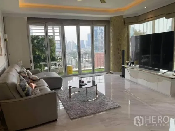 公寓 出售在Pathum Wan, Bangkok - 采光充足的客厅，石材地面，转角沙发，落地窗通向观景阳台与城市天际线。