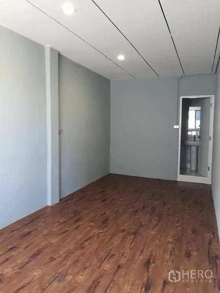 Shophouse for rent in Phra Khanong, Bangkok - Narrow room with wood-style flooring leading to an ensuite bathroom.