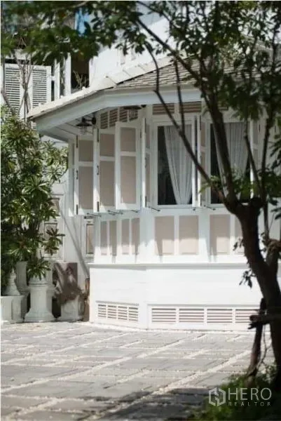 独立式住宅 出租在Bang Rak, Bangkok - 白色两层住宅的转角凸窗与铺石庭院。
