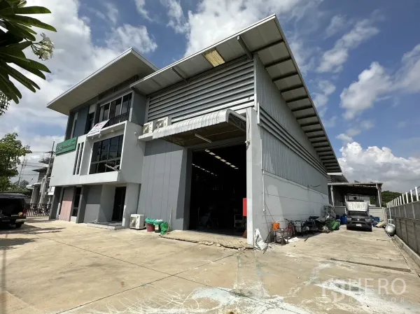 Factory for rent or sale in Pathum Thani - Front facade with open loading bay, warehouse entrance and parking area.