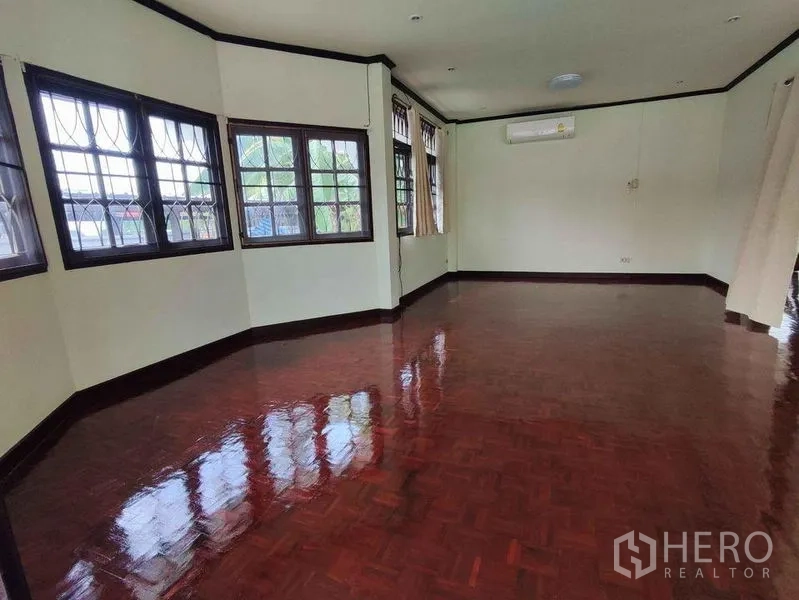 独立式住宅 出租在Khlong Toei, Bangkok - 宽敞客厅，亮面拼花木地板，多扇带防盗格的窗户与空调。