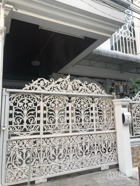 联排别墅 出租在Khlong Toei, Bangkok - 白色锻铁推拉门与带顶车库入口特写。
