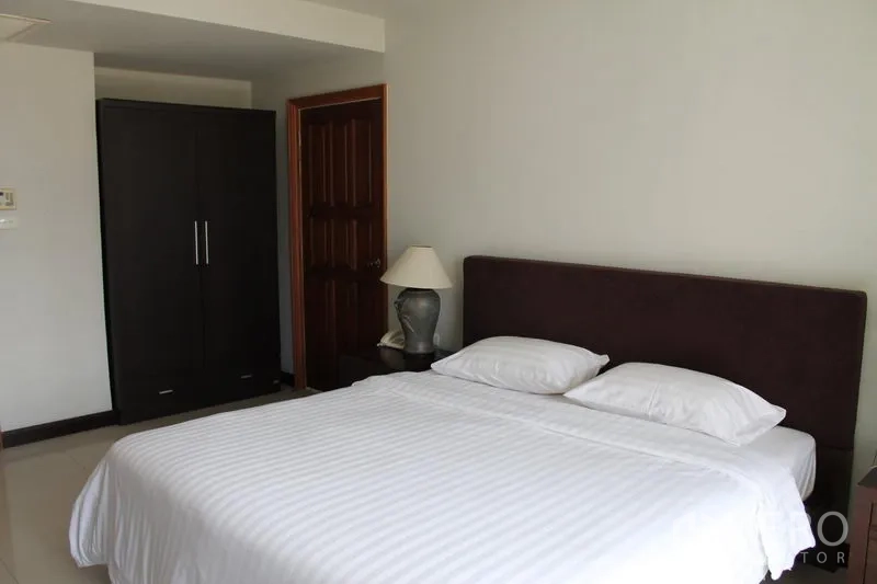 Apartment for rent in Bang Rak, Bangkok - Bedroom angle showing wardrobe and wooden door.