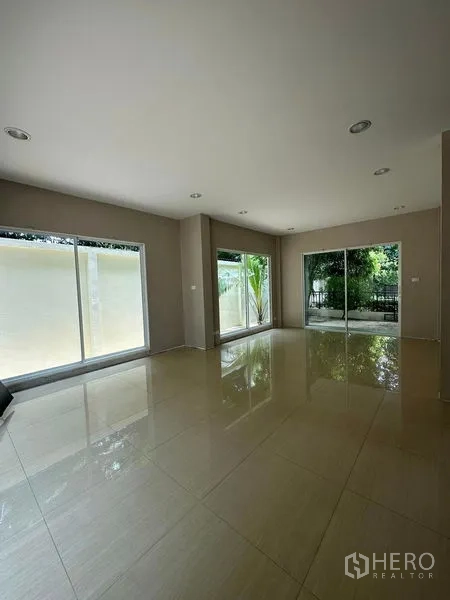 บ้าน ขายในPrawet, Bangkok - ห้องนั่งเล่นกว้าง พื้นกระเบื้องเงาและกระจกบานสูงเปิดสู่สวน ในเขตประเวศ กรุงเทพฯ