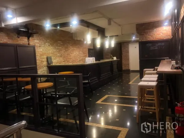 店屋 出租在Watthana, Bangkok - 餐厅吧台内饰，裸露红砖墙、深色木吧台与吊灯、咖啡式座位。