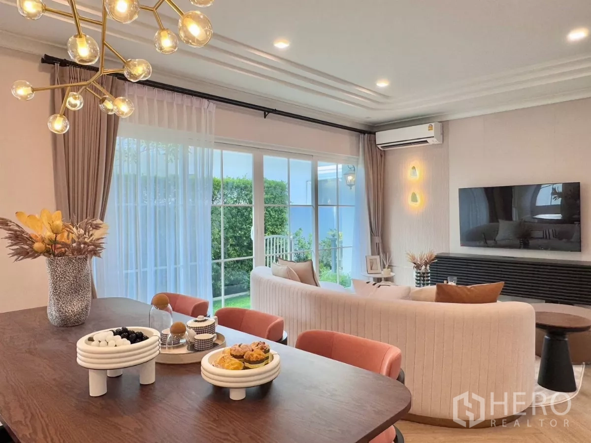 Detached House for rent in Bang Phli, Samut Prakan - Dining table beside TV wall and full-height glass doors overlooking greenery.