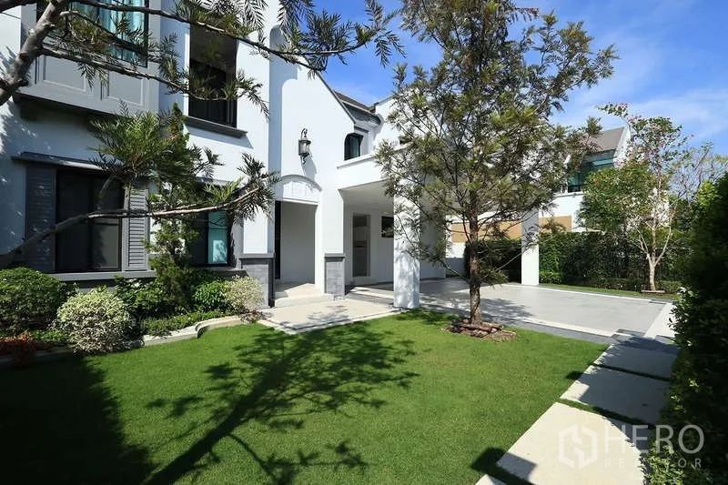 Detached House for rent in Saphan Sung, Bangkok - Landscaped front garden with green lawn, trees and paved walkway beside the house.