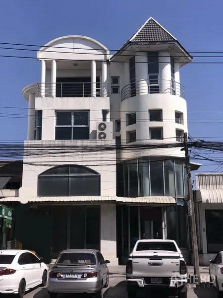 带办公室的家 出租在Saphan Sung, Bangkok - 曼谷主干道上的多层白色家用办公楼，带弧形阳台、大面积玻璃门面与前方停车位。
