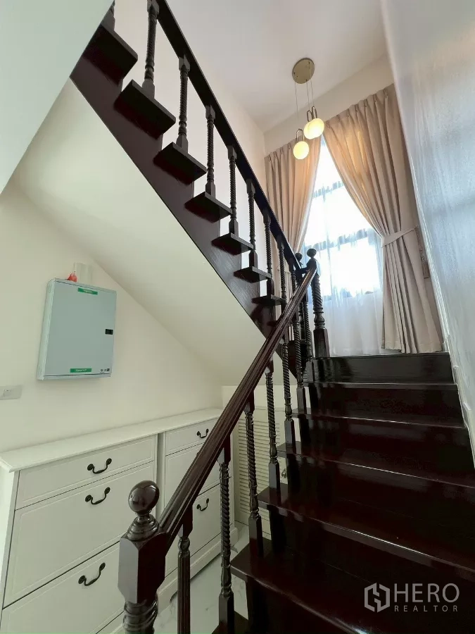 独立式住宅 出租在Suan Luang, Bangkok - 打磨光亮的深色木楼梯，经典扶手与高窗。