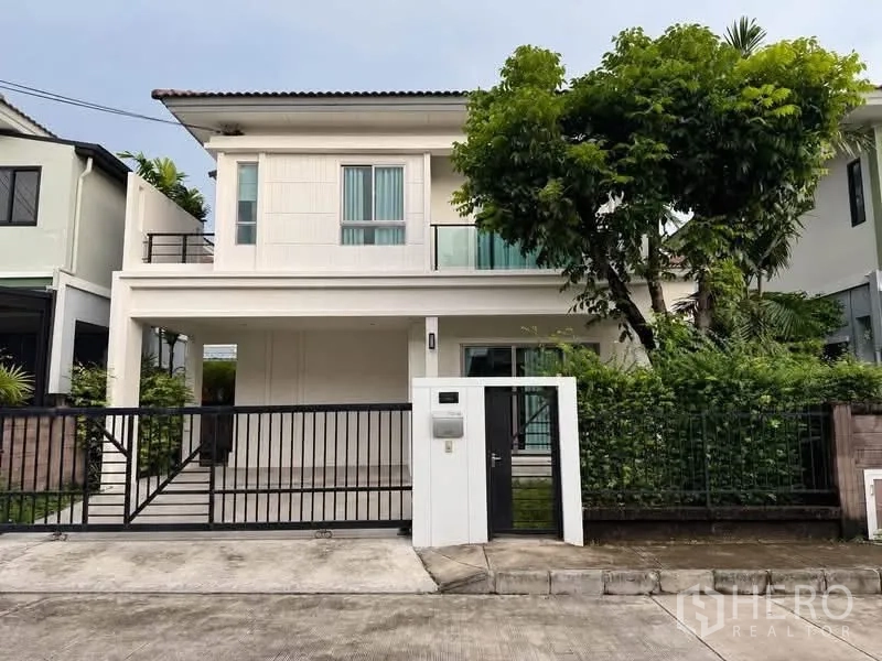 半独立式住宅 for rent or sale in Suan Luang, Bangkok - 两层现代外观的双拼住宅，带有顶棚车位、阳台与前院大门。