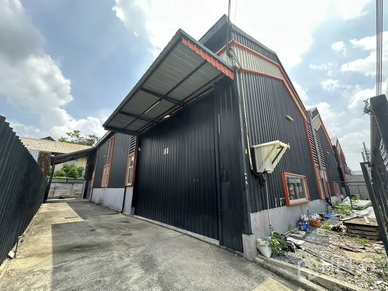 Warehouse for rent in Lat Phrao, Bangkok - Side driveway beside the corrugated metal warehouse with a covered loading canopy.