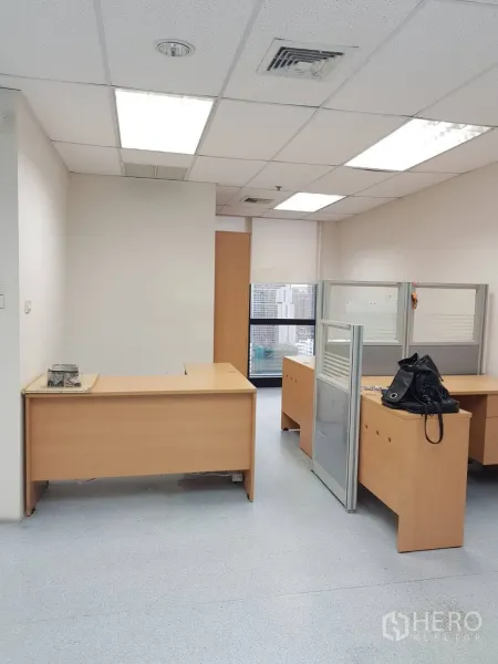 办公空间 出租在Bang Na, Bangkok - 开放式工位区，浅木色办公桌与隔板，明亮嵌灯与城市窗景。
