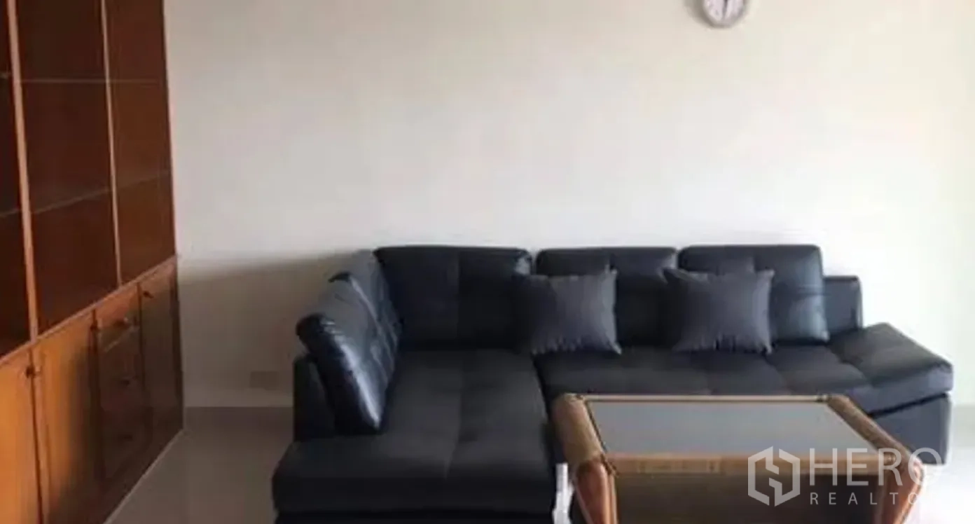 คอนโด for sale in Watthana, Bangkok - โซฟาหนังรูปตัวแอล โต๊ะกลางกระจก และตู้บิลท์อินในห้องนั่งเล่น