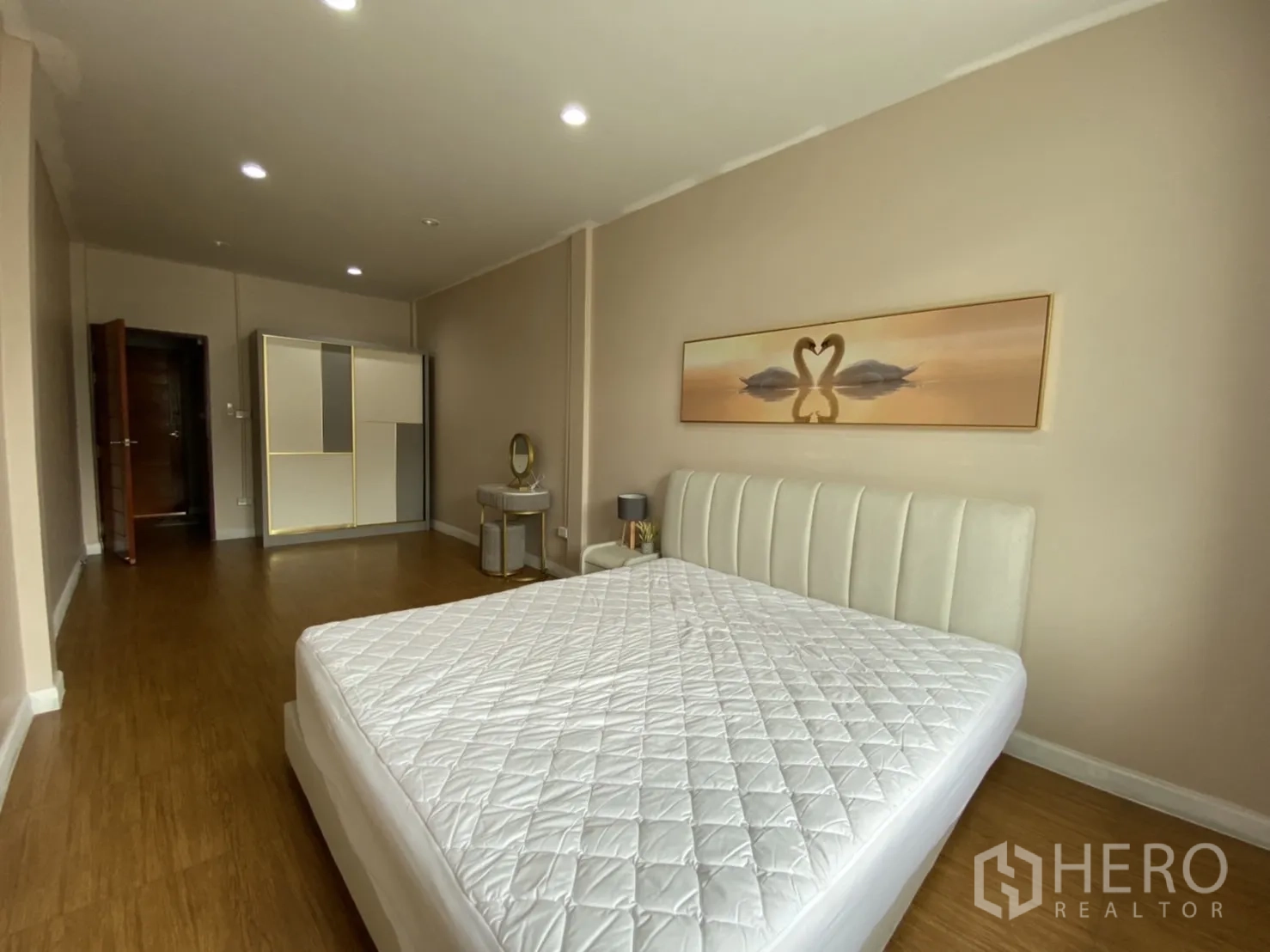 Townhouse for rent or sale - Large master bedroom with upholstered bed, wardrobe and wood flooring.