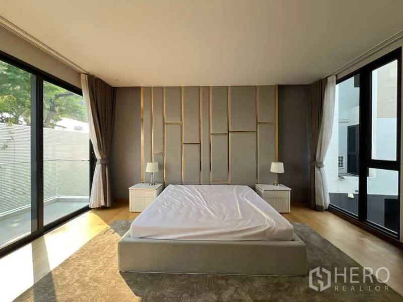 Detached House for rent in Suan Luang, Bangkok - Primary bedroom with padded feature wall, large windows and balcony access.