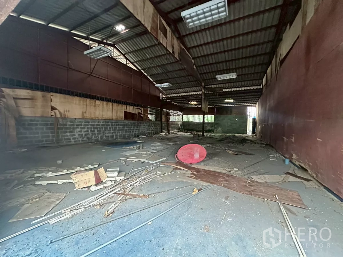 Warehouse for rent or sale in Yan Nawa, Bangkok - Long storage bay with metal cladding, high ceiling and scattered materials on the floor.