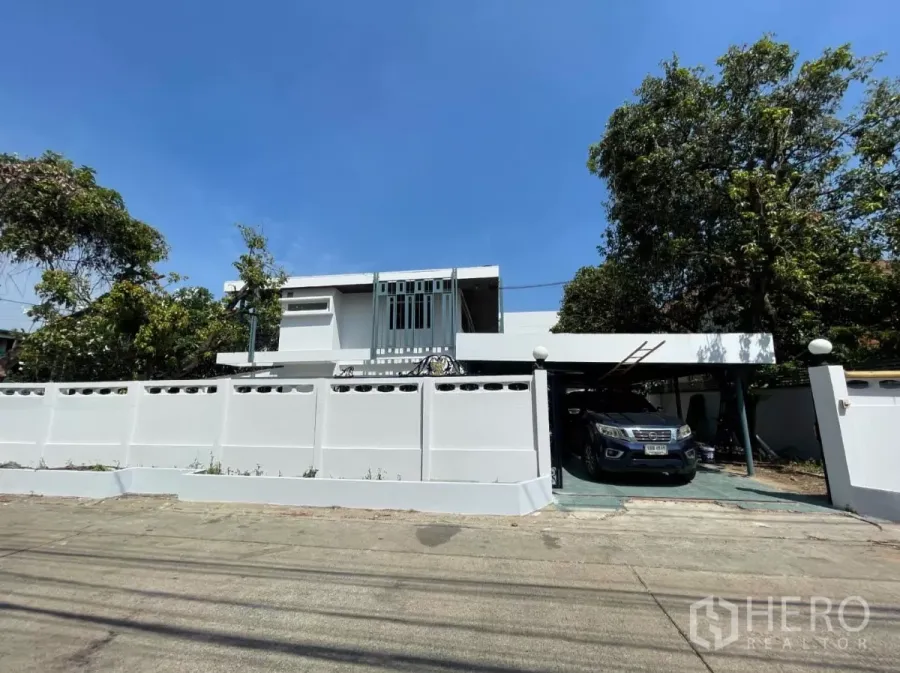 Home Office for rent in Din Daeng, Bangkok - Street view of a two‑storey white home office in Din Daeng with a high wall, gate and covered carport.