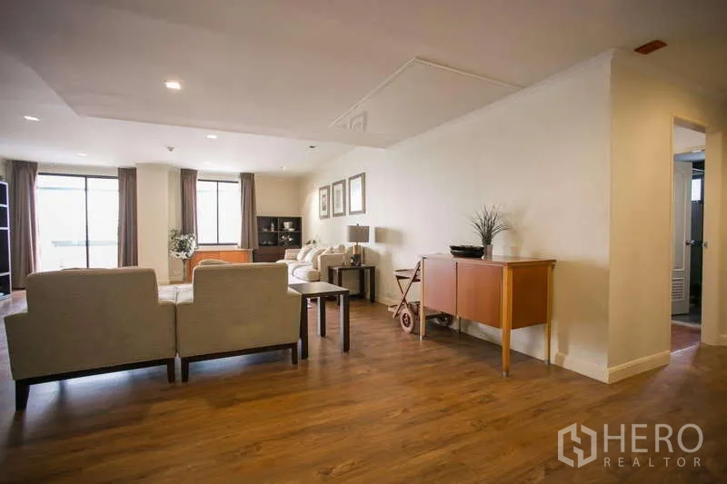 Condominium for rent or sale in Watthana, Bangkok - Living area side view with seating set, accent tables and wide windows.