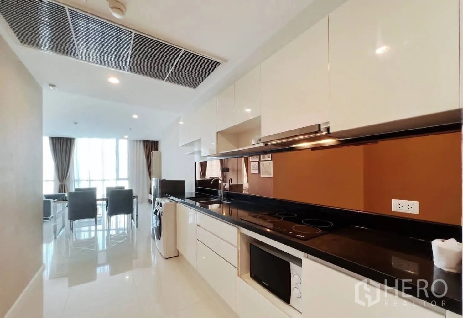 公寓 for rent in Watthana, Bangkok - 走廊式厨房配置亮面橱柜、电炉灶、抽油烟机、微波炉、冰箱和洗衣机。