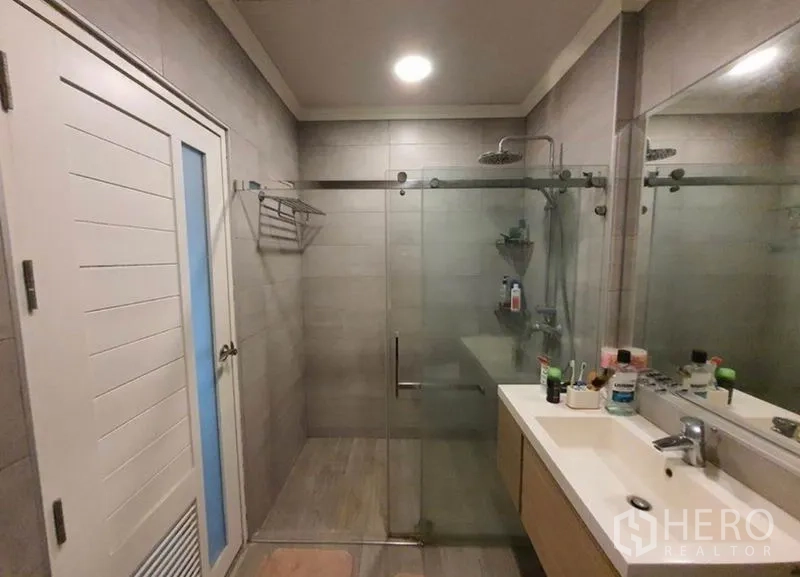Detached House for sale in Sai Mai, Bangkok - Modern bathroom featuring a glass-enclosed rain shower and a vanity with large mirror.