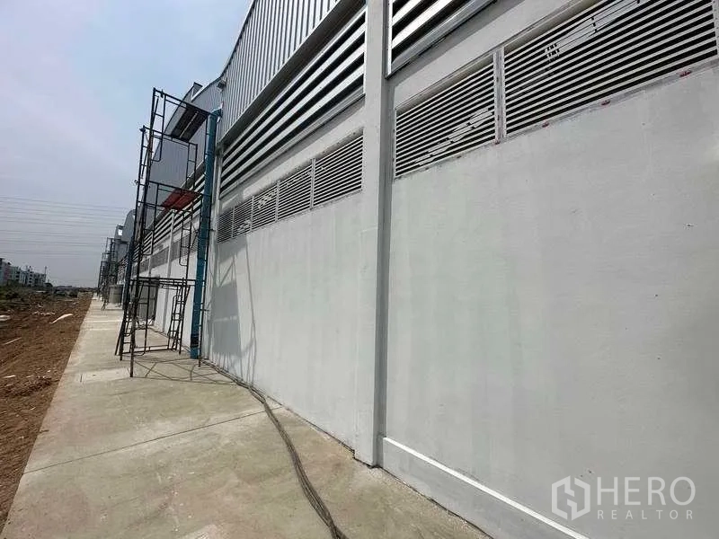 Factory for rent in Khlong Luang, Pathum Thani - Side elevation of the factory featuring ventilation louvers and a service walkway.