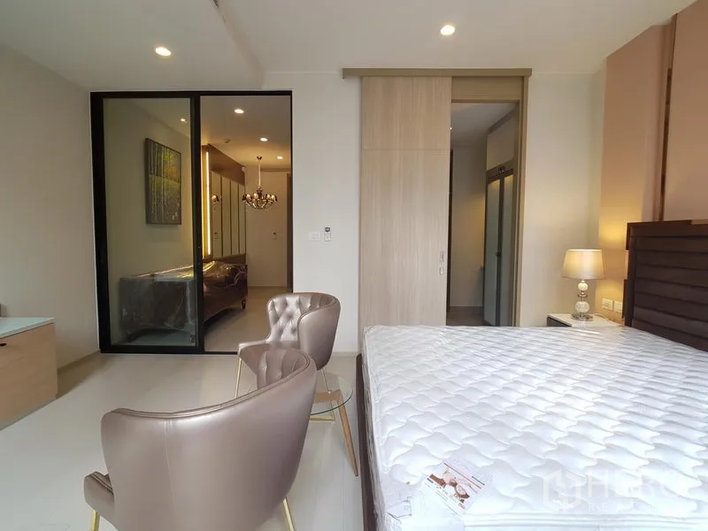 公寓 出租在Pathum Wan, Bangkok - 卧室望向起居区，玻璃推拉门、衣柜与床头灯
