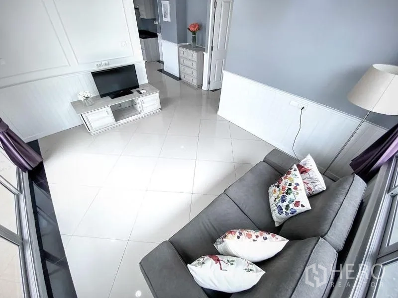 Condominium for rent in Khlong Toei, Bangkok - Bright living room with gray sofa, TV console, lamp and glossy tiled floors.