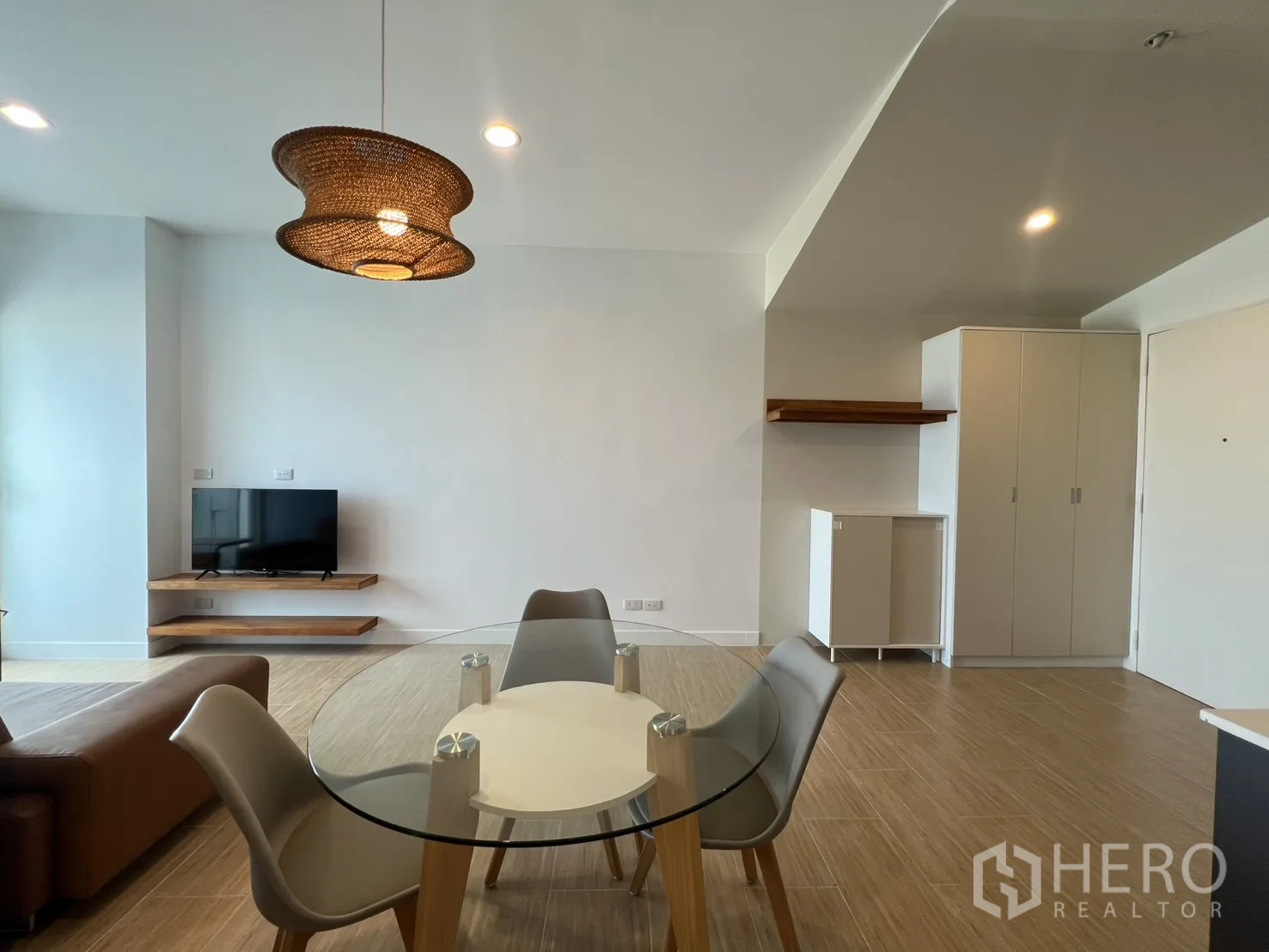 公寓 for rent in Bang Kapi, Bangkok - 壁挂电视置于木质悬浮层板上，对面为玻璃餐桌。
