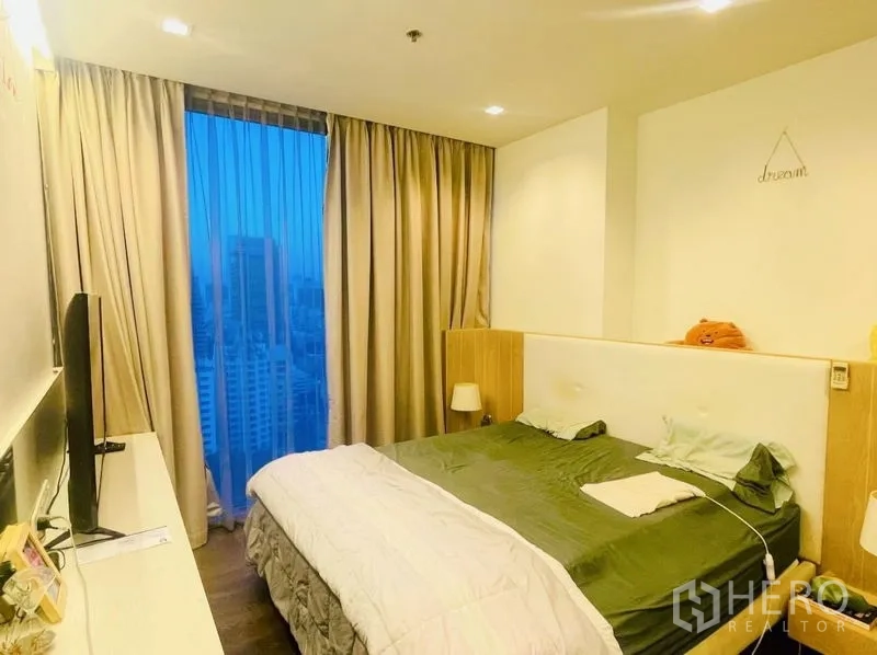 Condominium for rent or sale in Sathon, Bangkok - Master bedroom with large window, curtains and night city view.