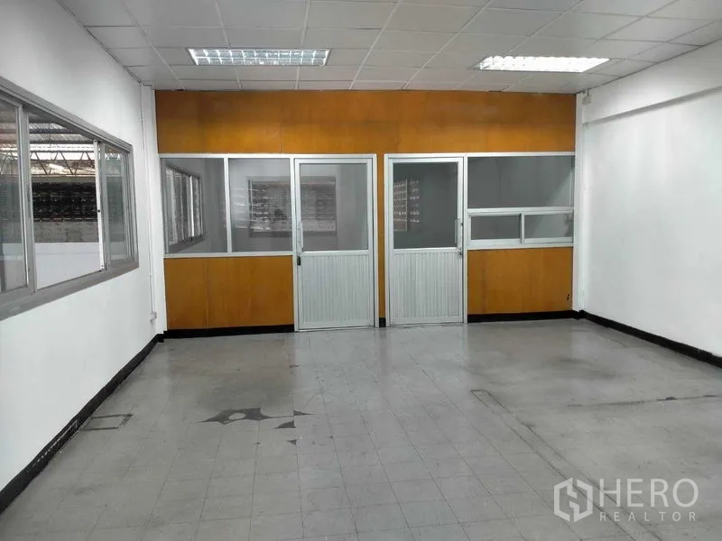 Warehouse for rent in Bang Phli, Samut Prakan - First-floor office area with glass partitions and fluorescent ceiling lights.