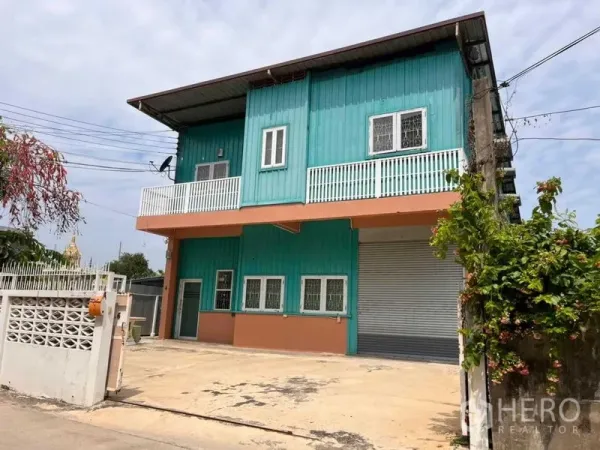 货栈 出租在Bang Phli, Samut Prakan - 两层青绿色仓库外立面，带卷闸门与阳台。