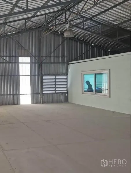 Warehouse for rent in Prawet, Bangkok - Warehouse interior featuring an enclosed office with window beneath a steel truss roof.