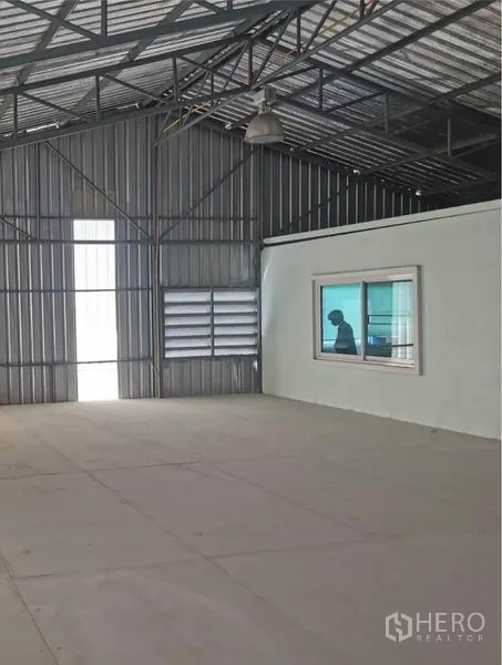 Warehouse for rent in Prawet, Bangkok - Warehouse interior featuring an enclosed office with window beneath a steel truss roof.