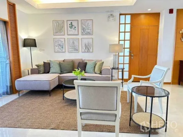 Apartment for rent - Cozy living room with L‑shaped sofa, accent chairs and botanical wall art in a modern Sathon Bangkok apartment.