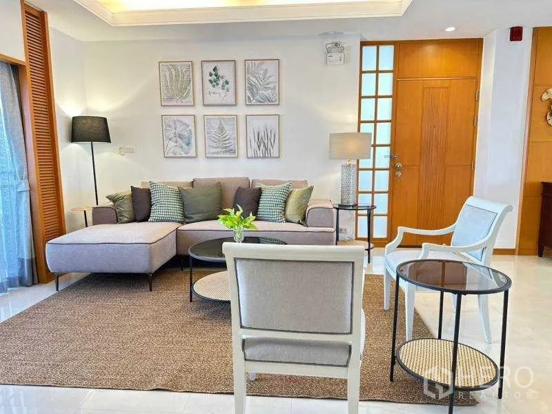 Apartment for rent - Cozy living room with L‑shaped sofa, accent chairs and botanical wall art in a modern Sathon Bangkok apartment.
