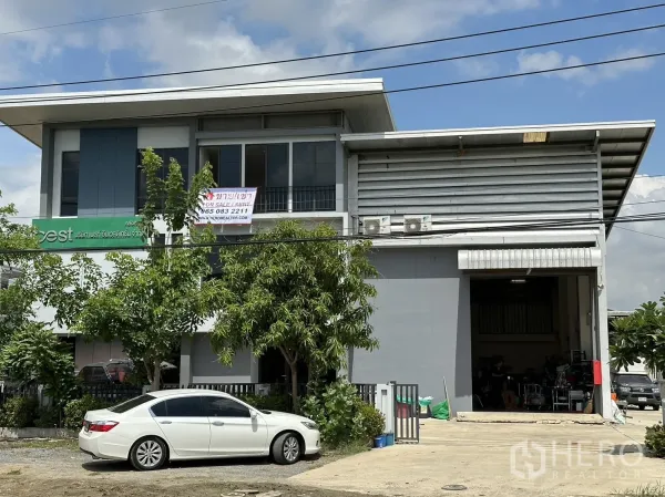 โรงงาน ให้เช่าหรือขายในPathum Thani - หน้าอาคารโรงงานขนาดกะทัดรัด ติดถนน พร้อมสำนักงาน 2 ชั้นและประตูม้วนใหญ่ มีที่จอดรถด้านหน้า.