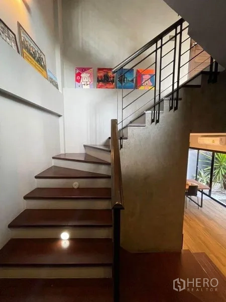 Townhouse for sale in Bang Phli, Samut Prakan - Staircase with wooden treads, metal balustrade and artwork along the wall.